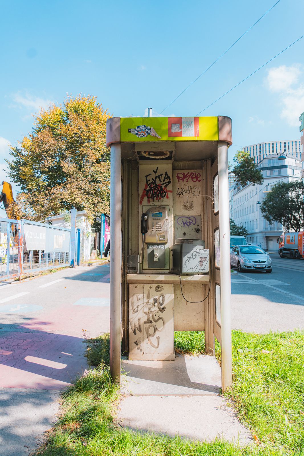 City photo — old phone booth covered in stickers and graffiti
